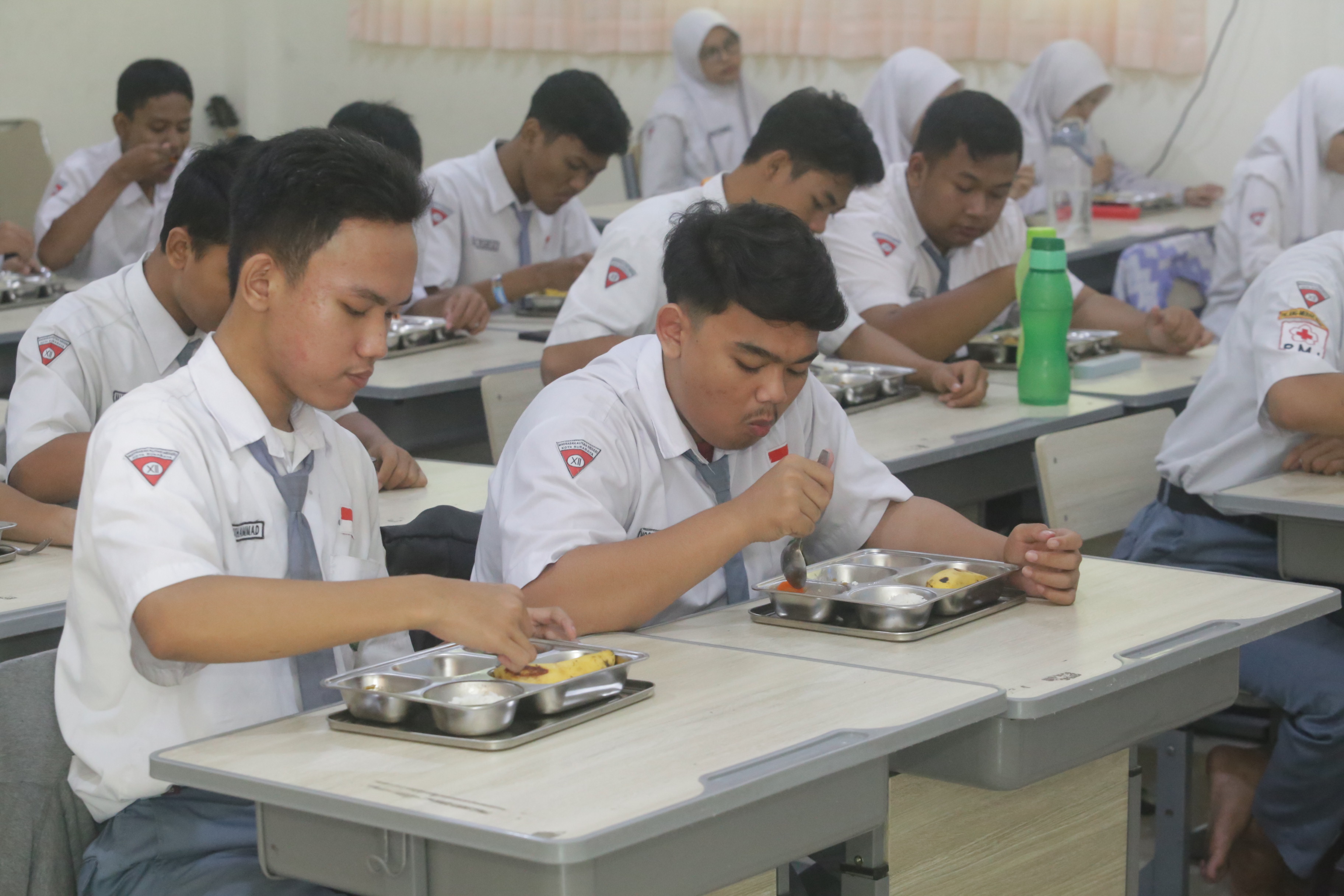 Sejumlah siswa menikmati makanan bergizi gratis di salah satu sekolah di Surabaya.
