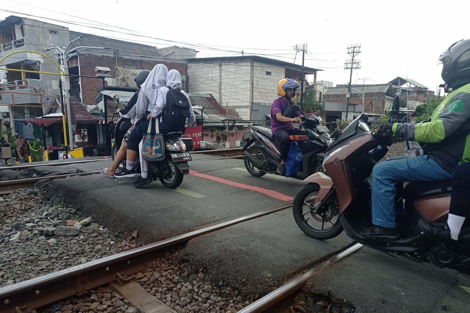 Pengendara kendaraan bermotor melintasi perlintasan kereta api di kawasan Gubeng, Surabaya.&nbsp;