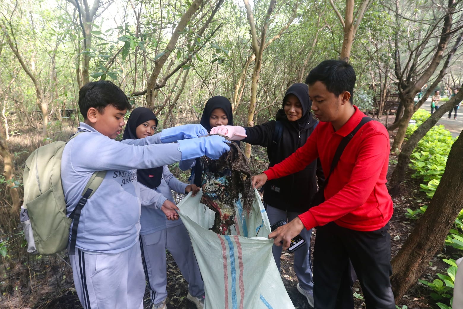 JAGA EKOSISTEM PESISIR: Sejumlah pelajar melakukan aksi bersih-bersih mangrove di Kebun Raya Mangrove Gunung Anyar.