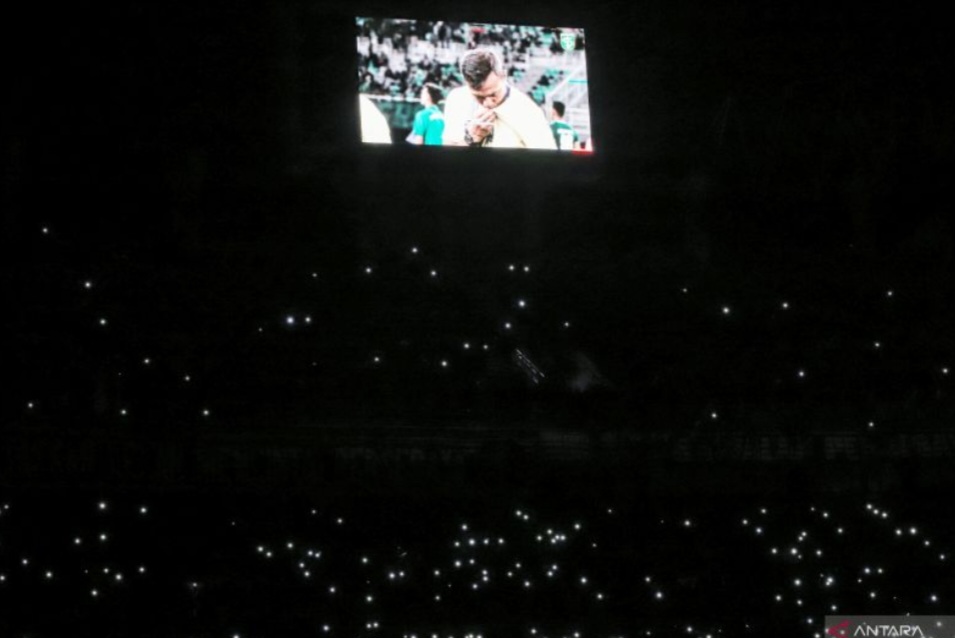 Suporter menyalakan lampu penerangan saat aksi "One Minute Silent Tribute To Bejo Sugiantoro" sebelum pertandingan melawan Persib Bandung, di Stadion GBT Surabaya, Sabtu (1/3) malam.
