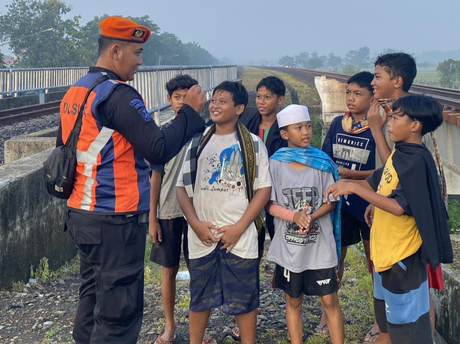 DILARANG: Petugas Polsuska dari PT KAI Daop 8 Surabaya mengedukasi anak-anak agar tidak ngabuburit di area steril sekitar jalur kereta api.