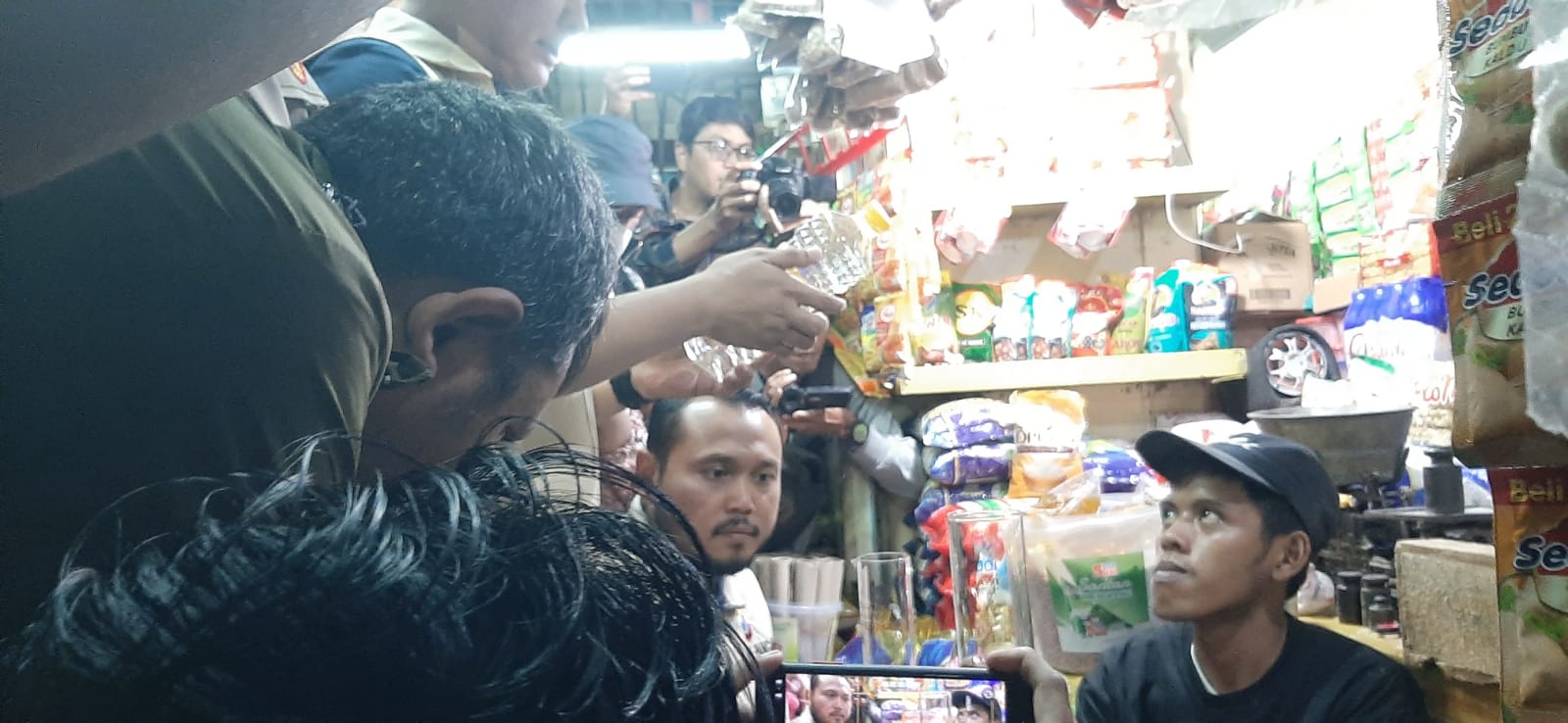 DIUKUR : Tim Satgas Pangan Polda Jatim saat melakukan pengukuran volume Minyakita kemasan botol menggunakan bejana ukur di kios Pasar Wonokromo, Surabaya. (IST)