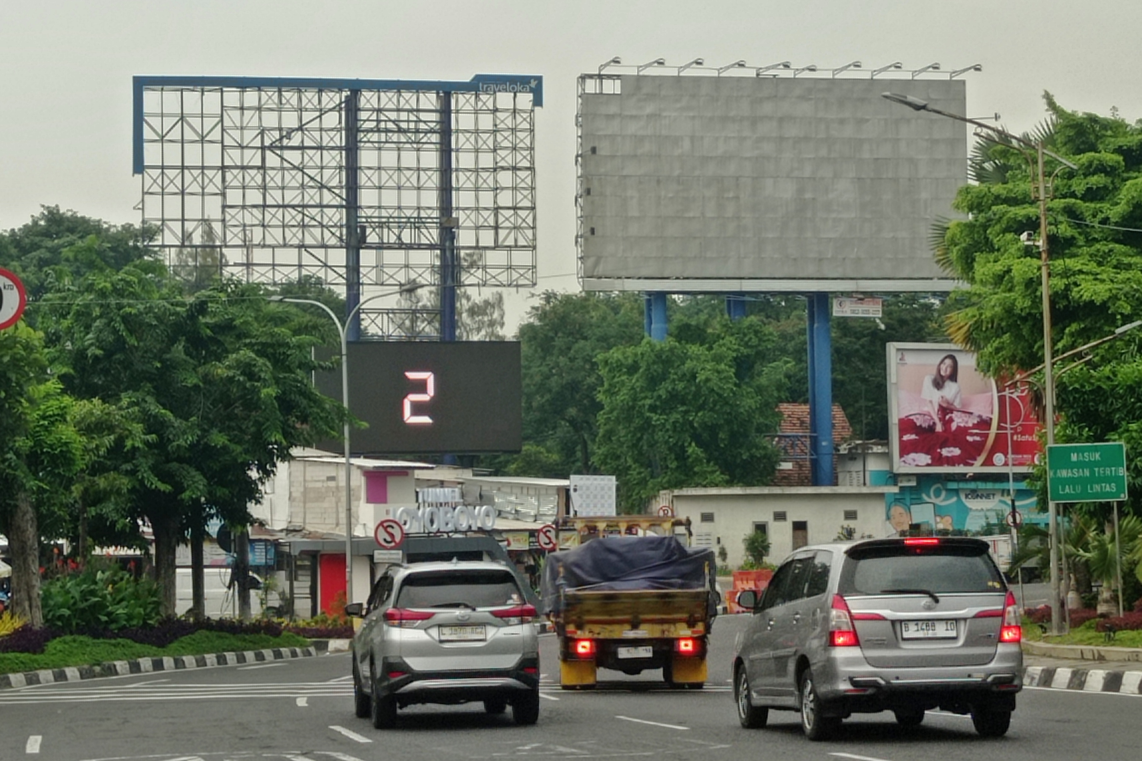 Pengendara kendaraan bermotor melintas tak jauh dari reklame yang terpasang di jalan Ahmad Yani, Surabaya.