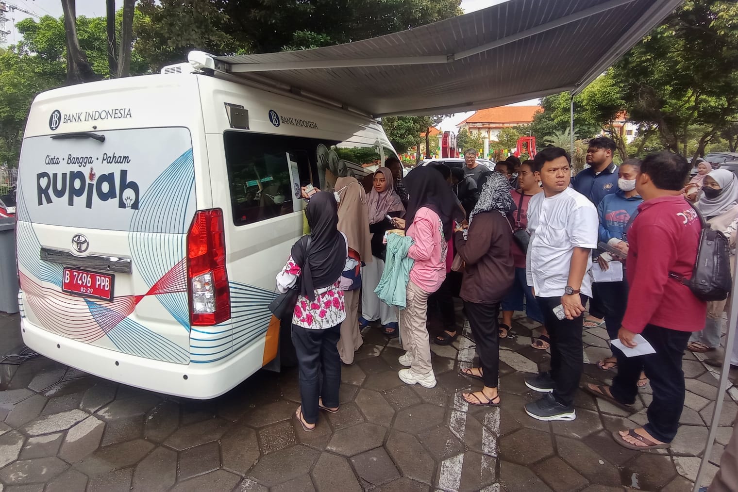 Warga antre menukarkan uang baru di mobil kas keliling Bank Indonesia yang tersedia di halaman Masjid Al Akbar, Surabaya.