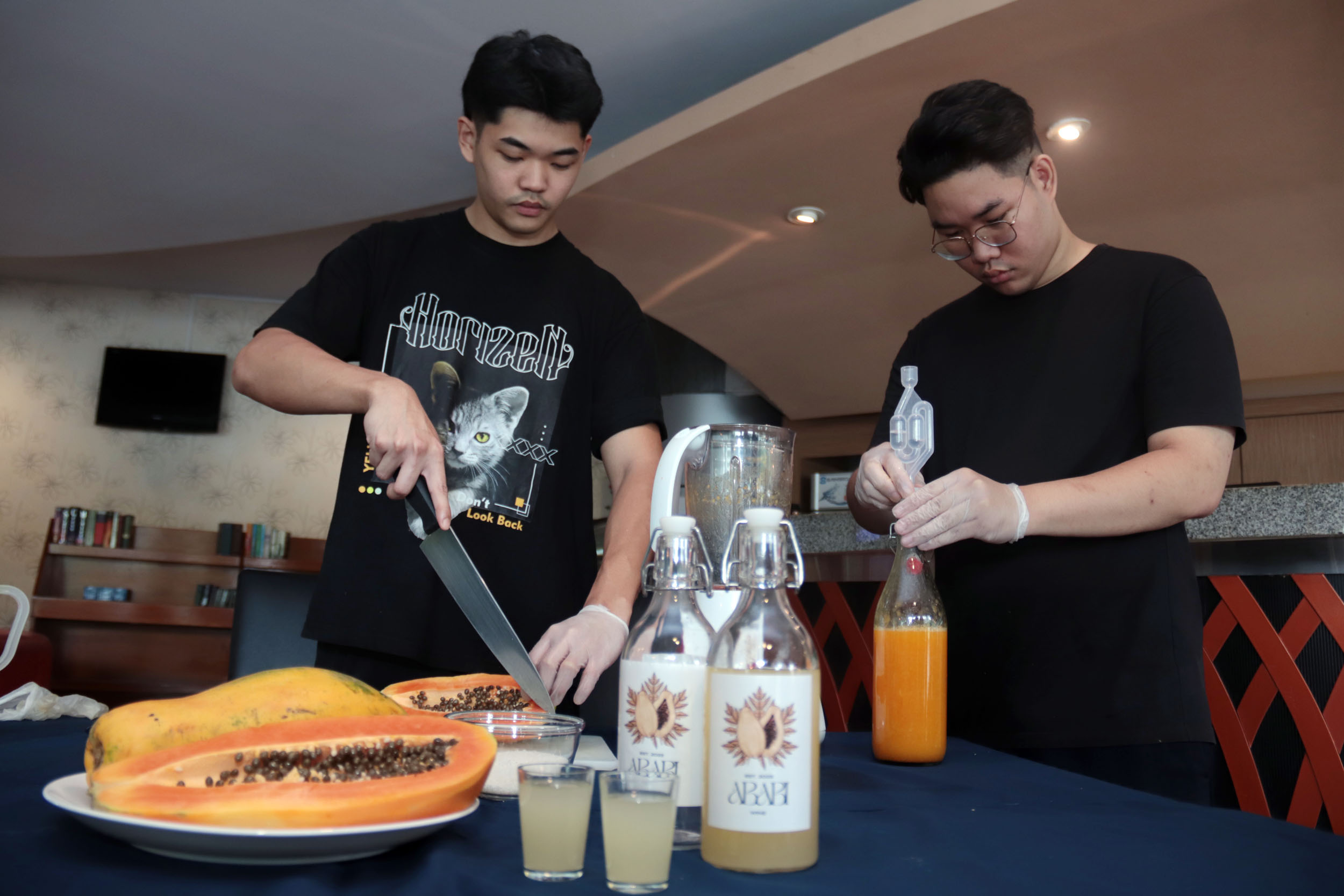 INOVATIF: Mahasiswa PCU, Cleary Budiman dan Davin Varian menunjukkan proses pembuatan wine dengan memanfaatkan buah pepaya sebagai bahan bakunya, di kampus setempat.