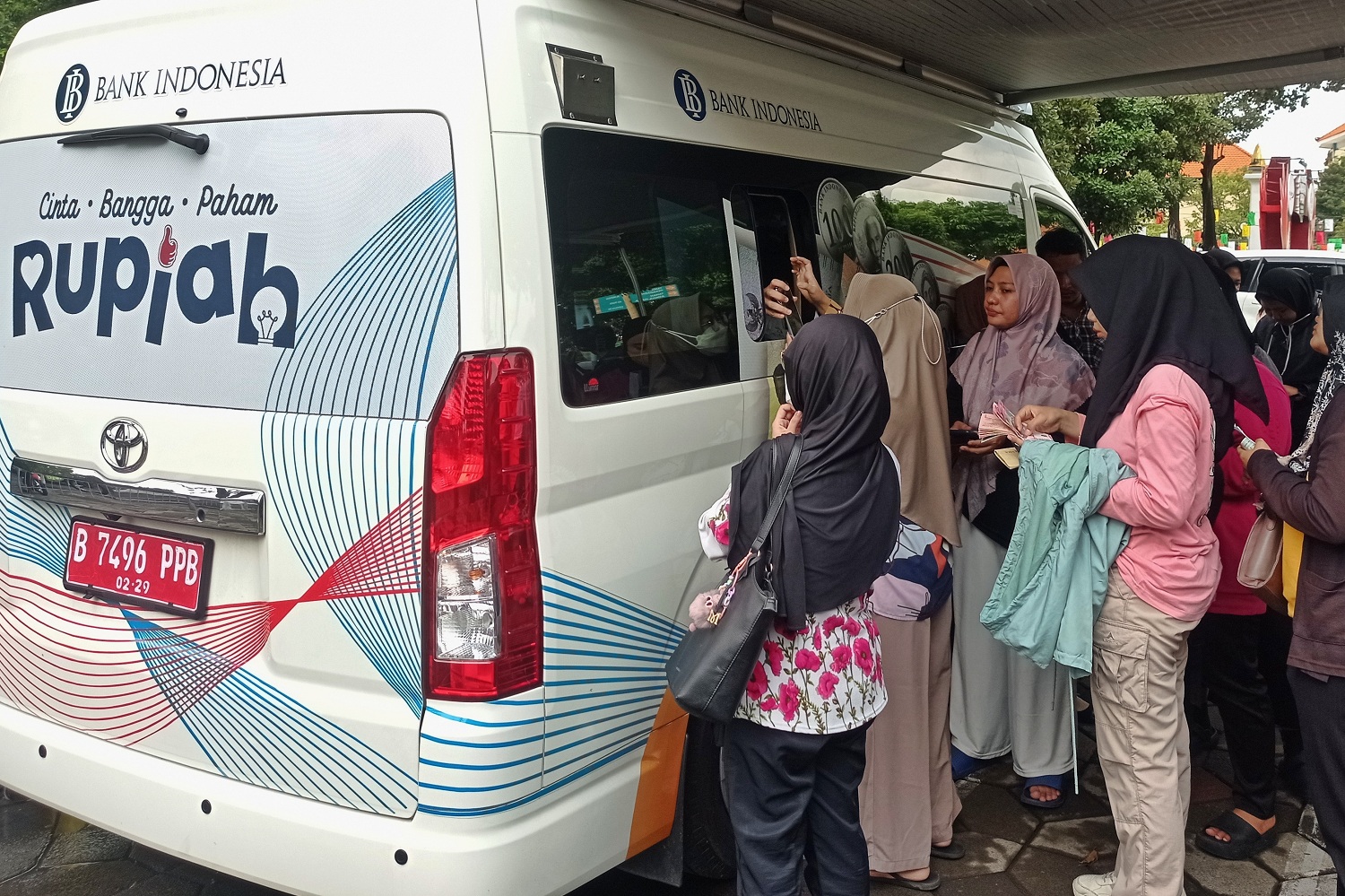 Warga antre menukarkan uang baru di mobil kas keliling Bank Indonesia yang tersedia di halaman Masjid Al Akbar, Surabaya.
