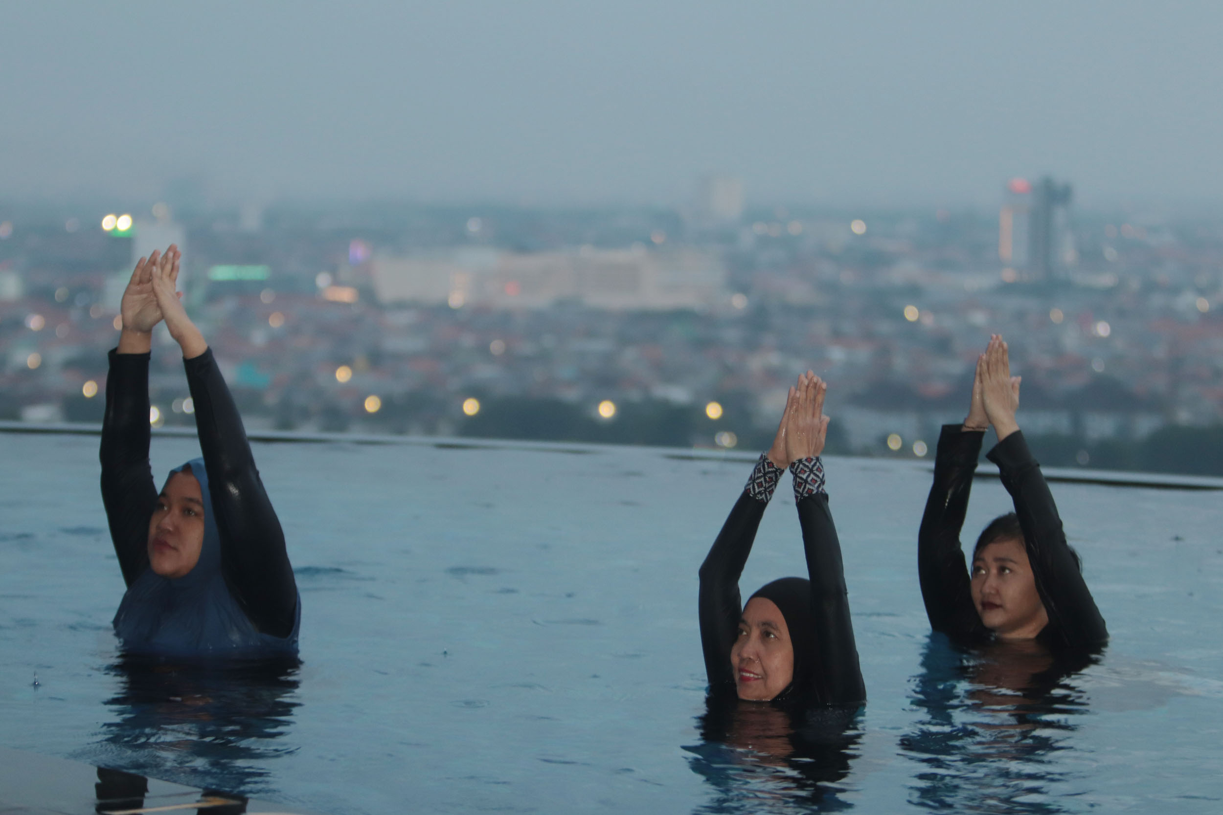 BANYAK MANFAATNYA: Para peserta mengikuti gerakan yang diarahkan instruktur, dalam kegiatan Aqua Yoga untuk menunggu waktu berbuka puasa di kolam renang Hotel Ciputra World Surabaya.