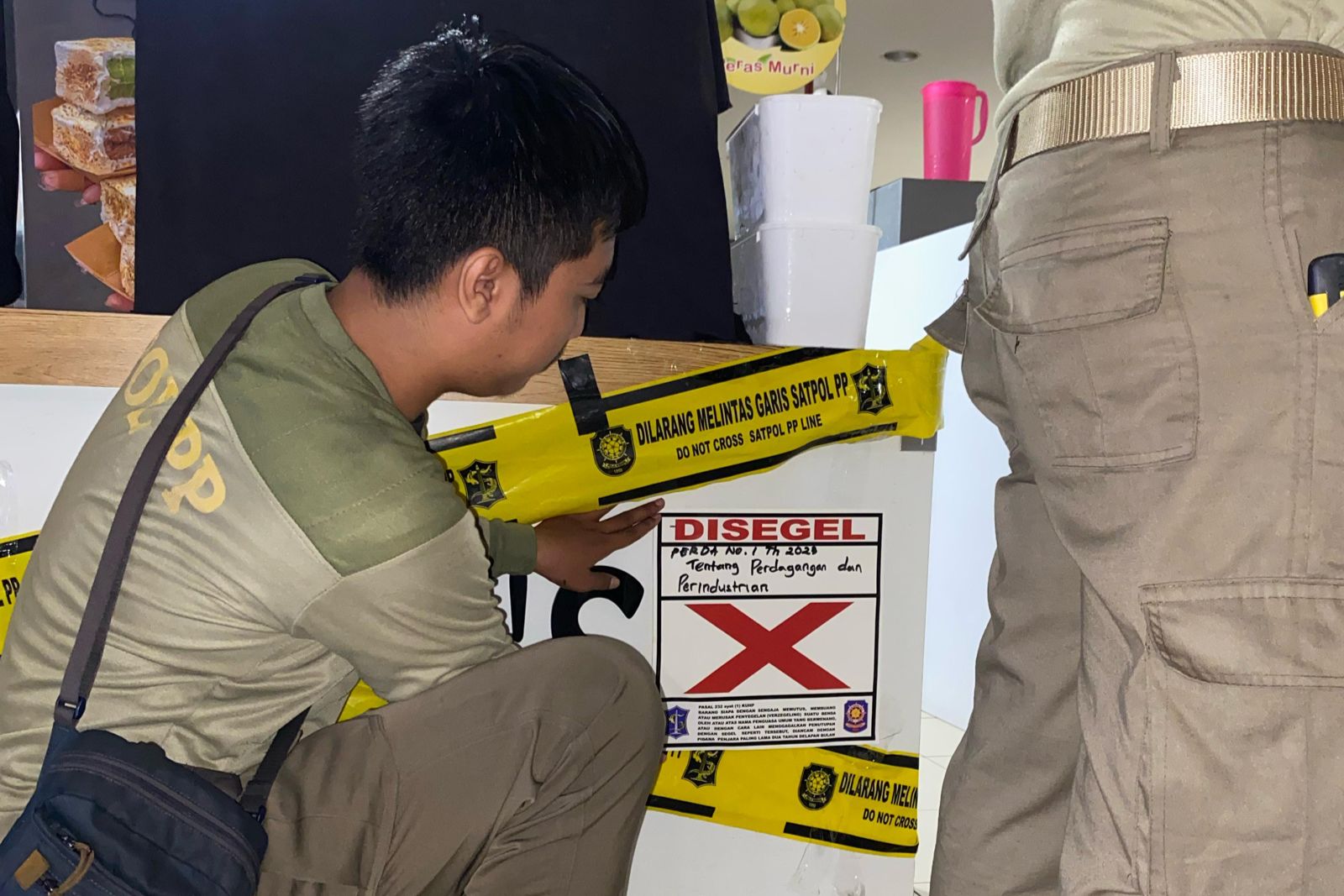 BERALKOHOL: Petugas Satpol PP Surabaya menempelkan stiker penyegelan dan pelanggaran di stan es krim yang berada di pusat perbelanjaan kawasan Surabaya Barat.
