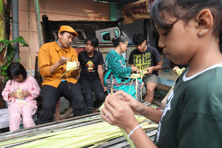 LESTARIKAN: Warga di Kenjeran Surabaya saat mengenalkan cara membuat ketupat kepada anak-anak.