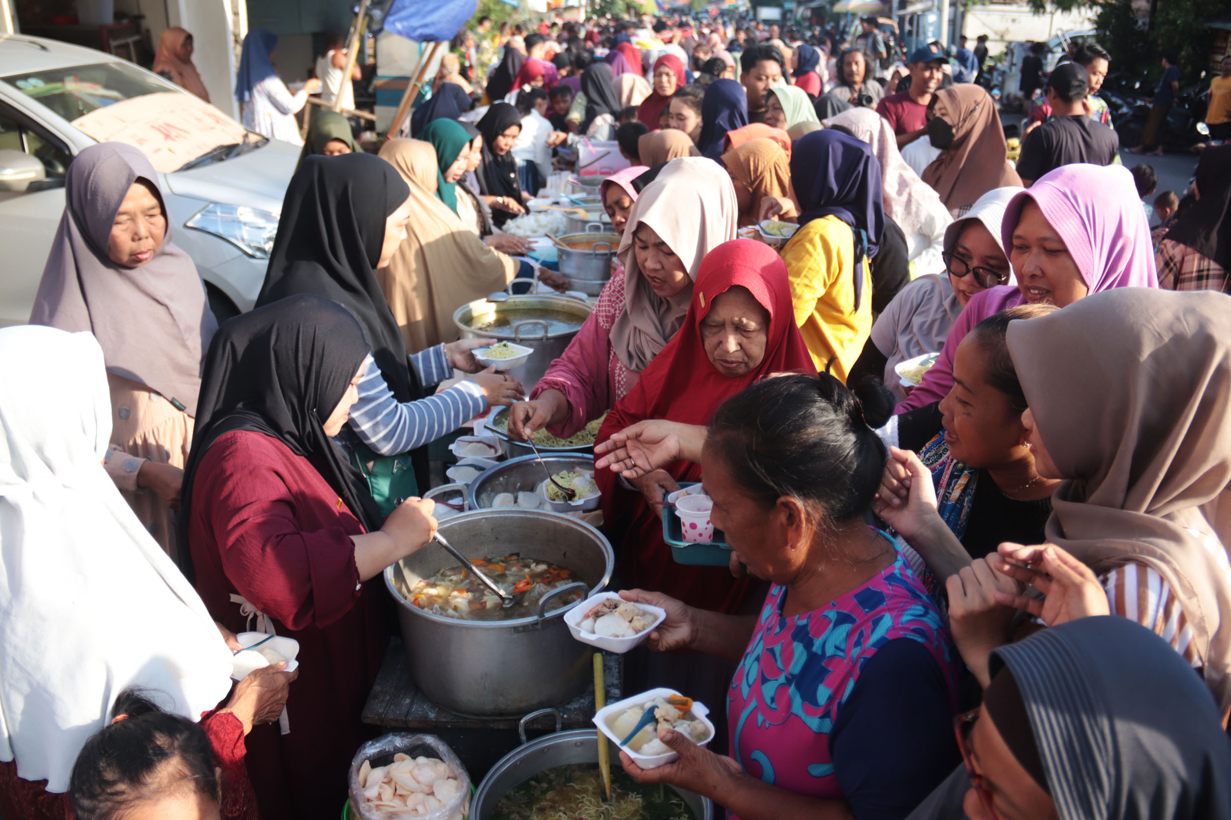 Ratusan masyarakat berebut makanan yang disediakan warga secara gratis di kawasan Sukolilo, Bulak, Surabaya, dalam rangka Lebaran Ketupat, Senin (7/4).