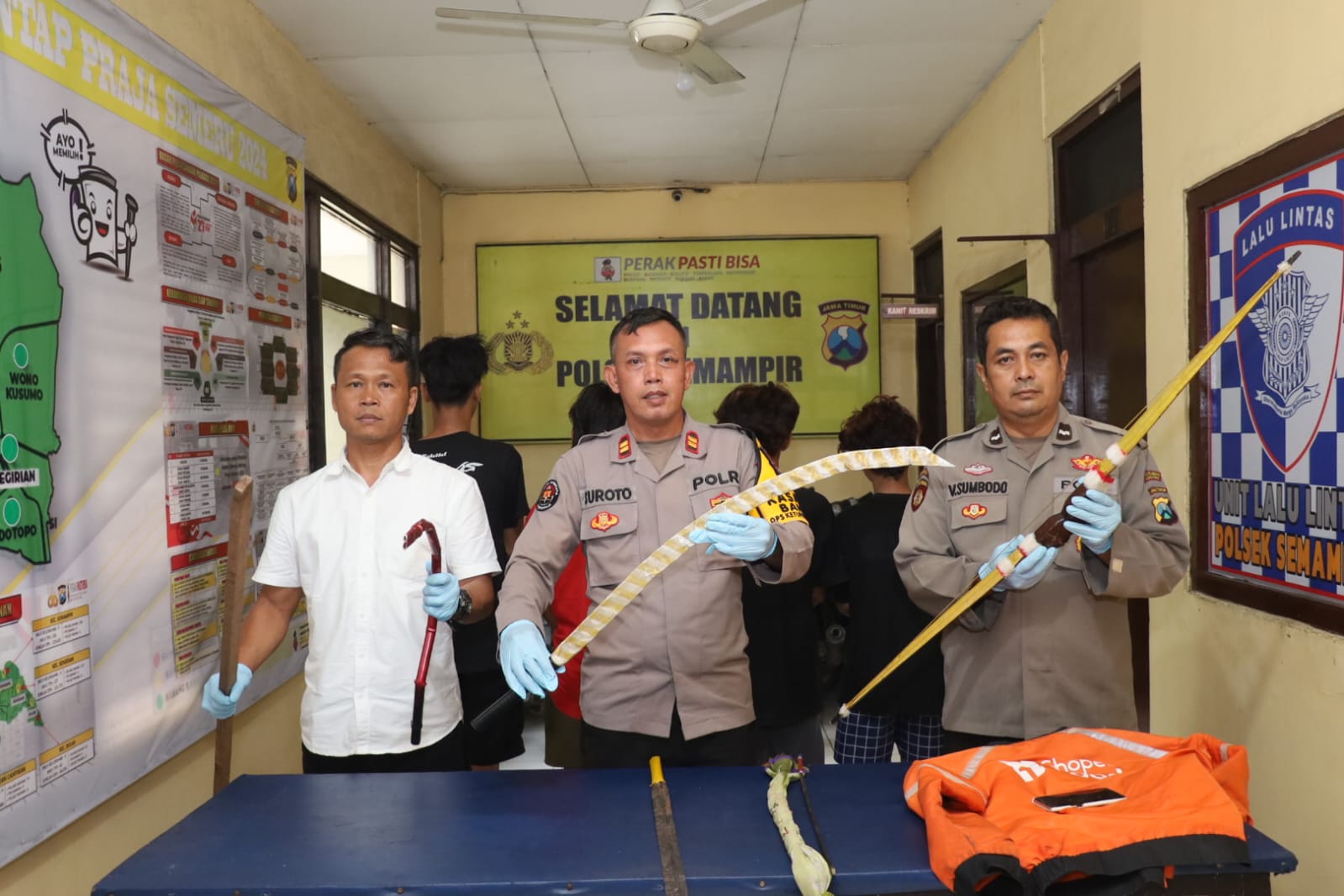 Petugas menunjukkan barang bukti sajam dan remaja yang diamankan usai tawuran di Tenggumung Karya Lor, Surabaya. (SURYANTO/RADAR SURABAYA)