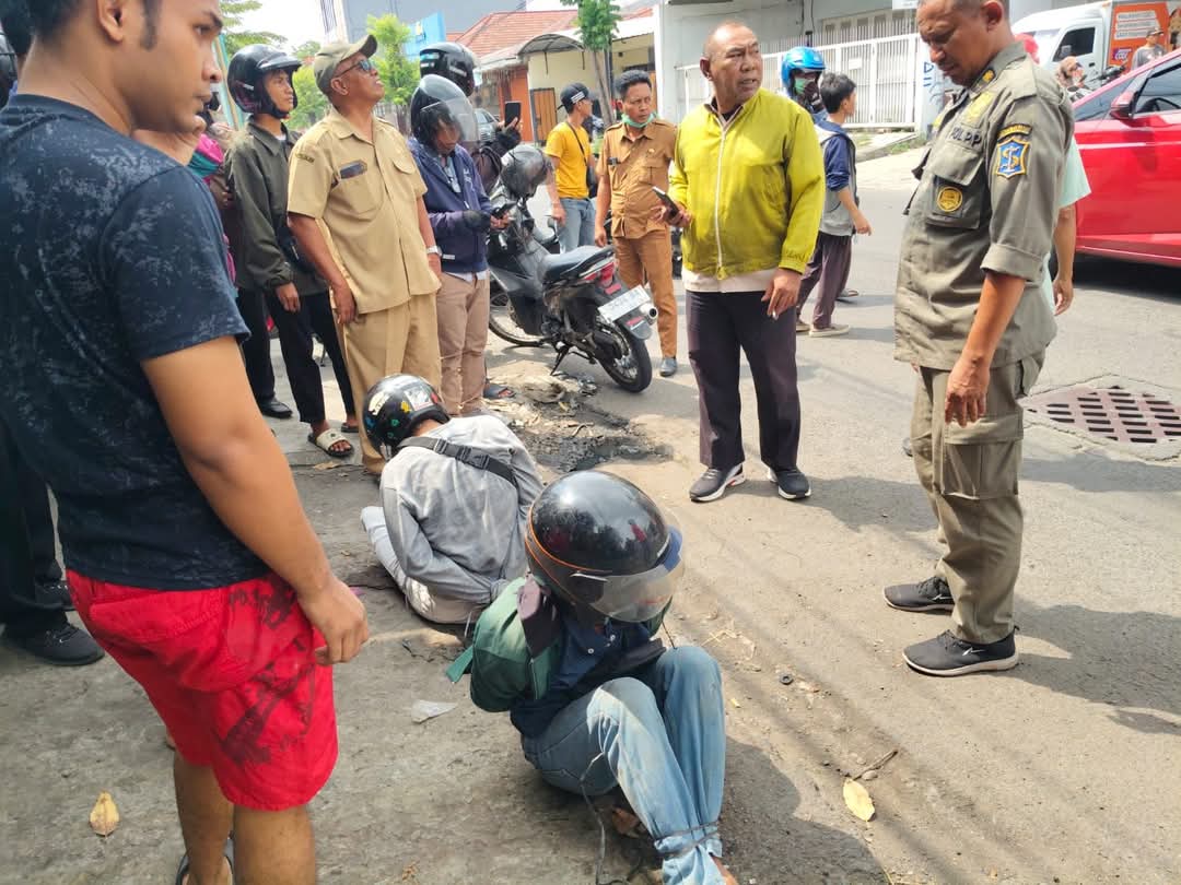 EFEK JERA: Dua pelaku pencuri helm diikat massa setelah terpergok beraksi di Darmo Indah Barat, Surabaya. (IST/RADAR SURABAYA)