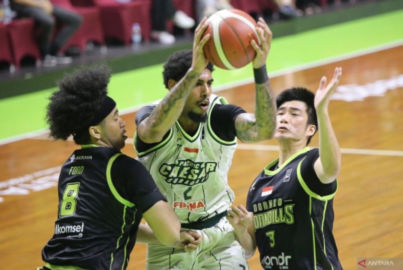 Pebasket Pacific Caesar Surabaya Adonnecy Joshua Bramah (tengah) berusaha melewati pebasket Borneo Hornbills Xavier Ford (kiri) dan Hans Abraham (kanan).