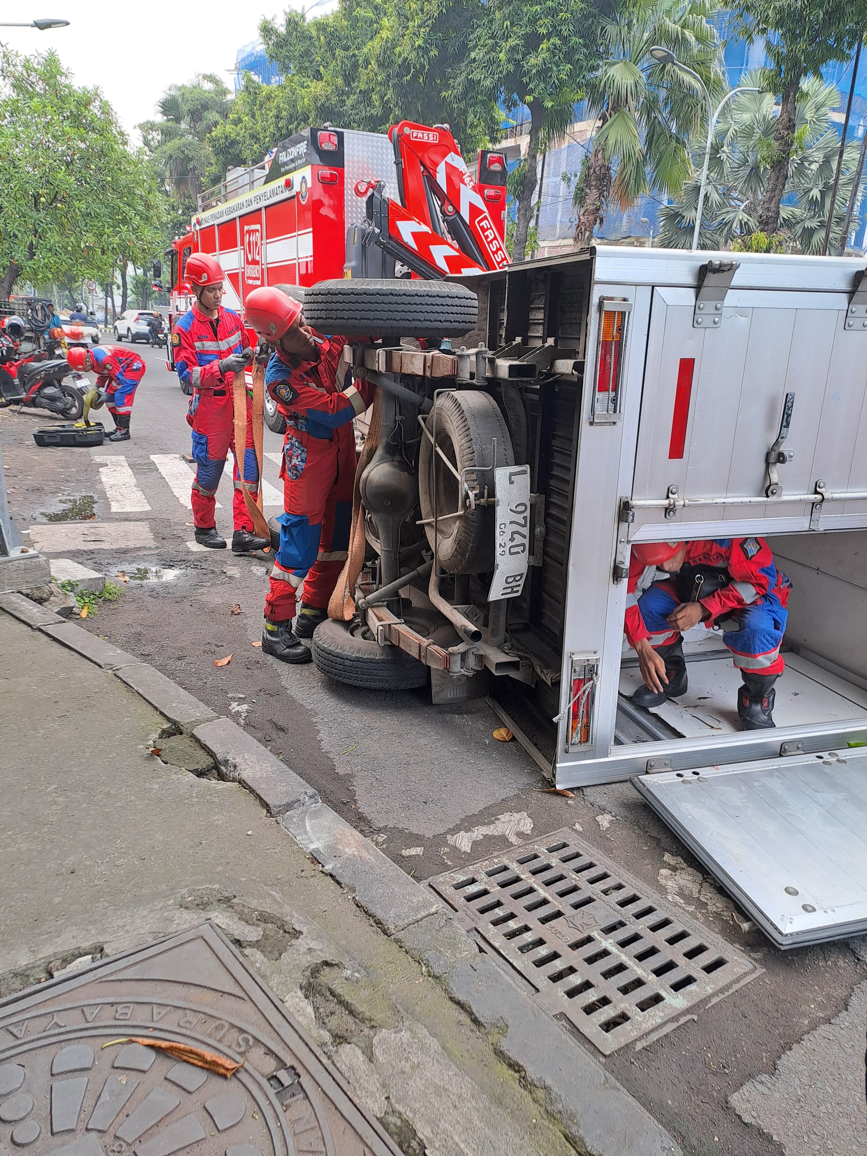 EVAKUASI : Petugas DPKP Surabaya saat mengevakuasi mobil boks yang terguling di Jalan Arjuno, Surabaya, Kamis (24/4). (IST/RADAR SURABAYA)