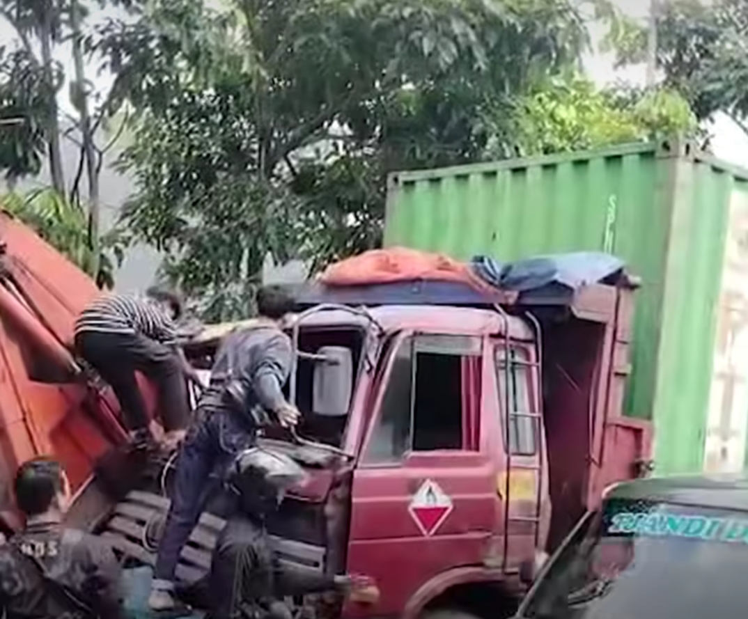 RINGSEK : Warga berupaya menolong sopir truk kontainer setelah kecelakaan menabrak truk sampah di Jalan Banjar Sugihan Baru, Tandes Surabaya, Sabtu (26/4). (IST/RADAR SURABAYA))