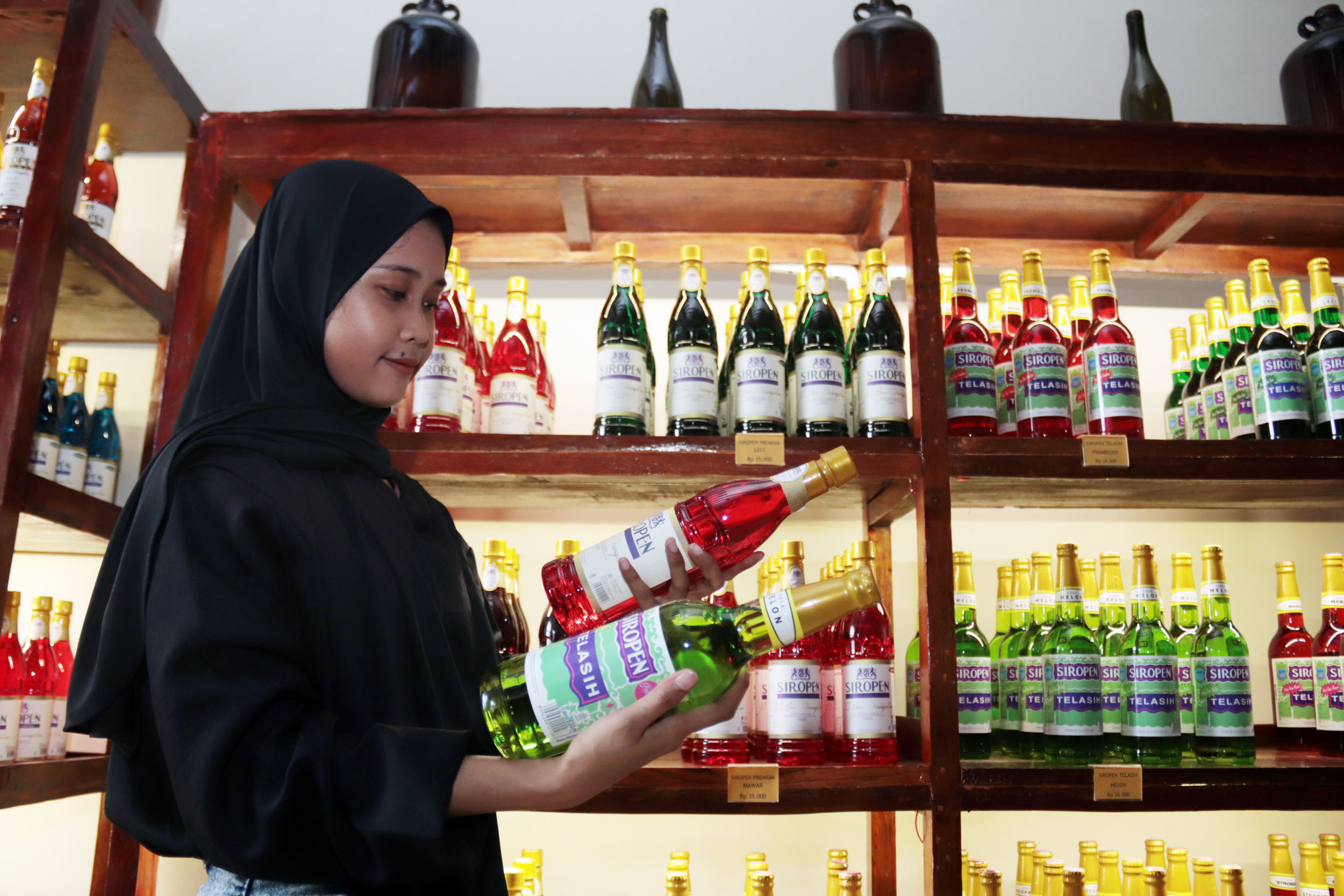 SIRUP LEGENDARIS: Petugas di Pabrik Siropen Surabaya menunjukkan beberapa varian rasa sirup yang diproduksi oleh pabrik legendaris tersebut, yang dipajang di area lobi pabrik di kawasan Kota Lama.