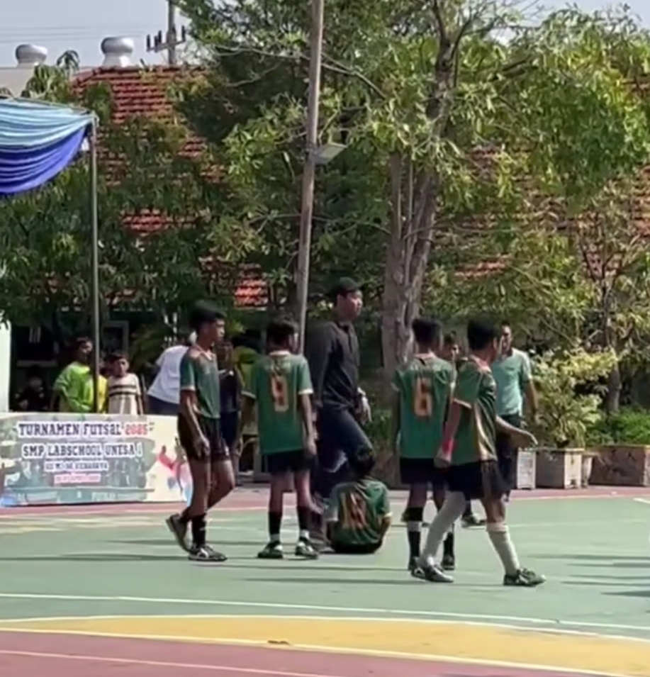 KEJADIAN : Pria berkaos hitam diduga pelatih tim lawan usai membanting korban saat selebrasi kemenangan pertandingan futsal antar SD di Surabaya. (IST/RADAR SURABAYA)