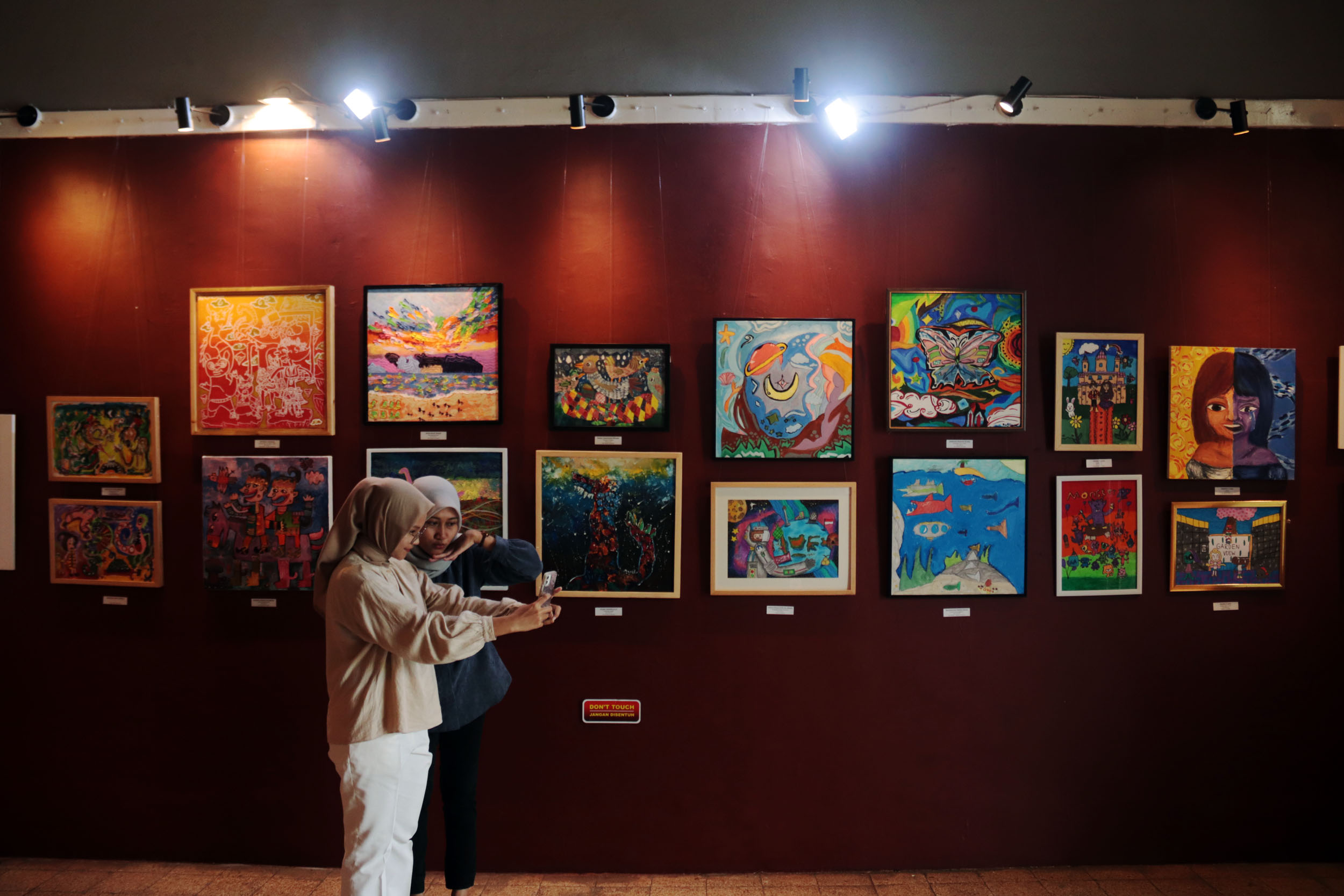 PENUH MAKNA: Pengunjung berswafoto foto diantara karya para seniman muda dalam pameran bertajuk Terbitlah Terang di Galeri Merah Putih, kompleks Alun-alun Kota Surabaya.