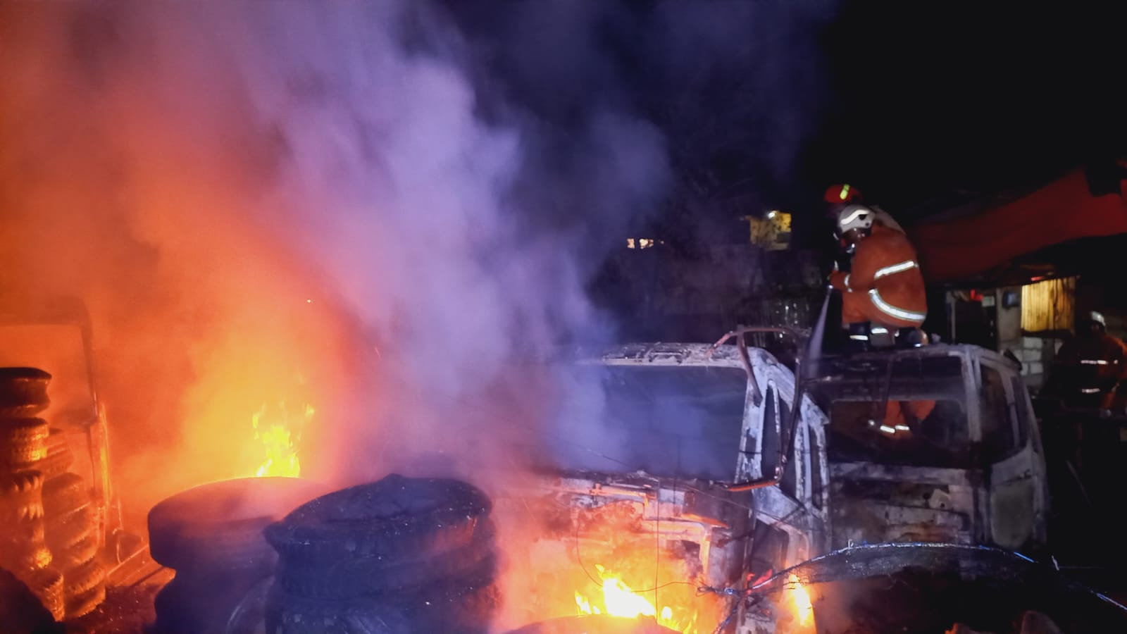MENYALA : Petugas berusaha memadamkan api yang membakar gudang besi tua di Kedinding Lor, Surabaya. (IST/RADAR SURABAYA)
