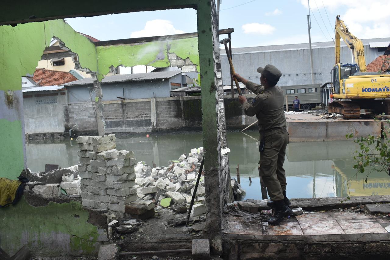 Patugas dari Satpol PP dan DSDABM Surabaya melakukan pembongkaran bangunan liar di bantaran Sungai Kalianak, Surabaya.