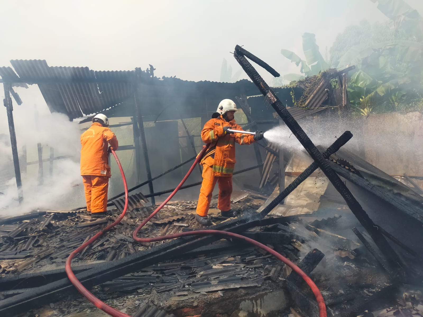 PEMADAMAN : Petugas DPKP memadamkan api di lokasi. Polisi masih menyelidiki penyebab kebakaran warung di Jalan Wonorejo Timur, Surabaya. (IST/RADAR SURABAYA)