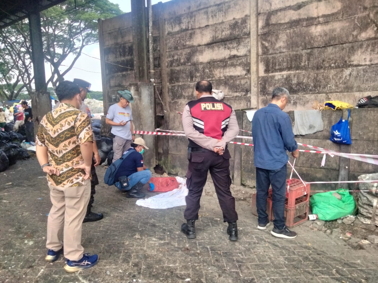PENYELIDIKAN: Polisi dan petugas TPA Jalan Alas Malang, Sambikerep, Surabaya, menemukan mayat bayi laki-laki dalam tas kresek merah. (IST/RADAR SURABAYA)