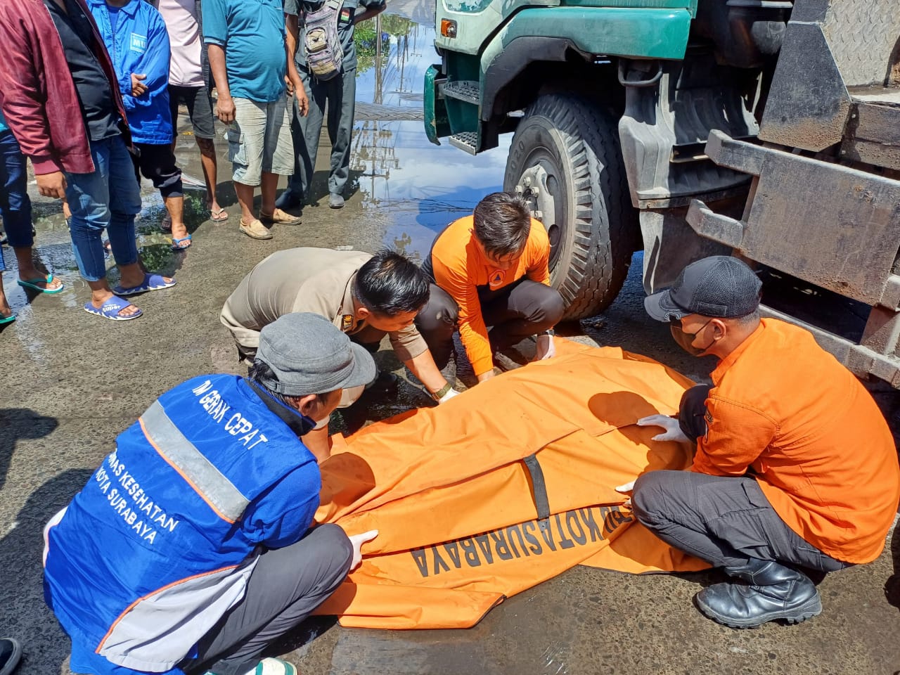 TRAGIS : Petugas mengevakuasi jasad korban kecelakaan truk dan sepeda motor di Jalan Greges Barat, Surabaya. (IST/RADAR SURABAYA)
