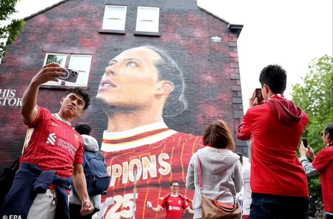 Para pendukung mengantre untuk berfoto di samping mural Virgil van Dijk beberapa jam setelah ia mengangkat trofi Liga Primer
