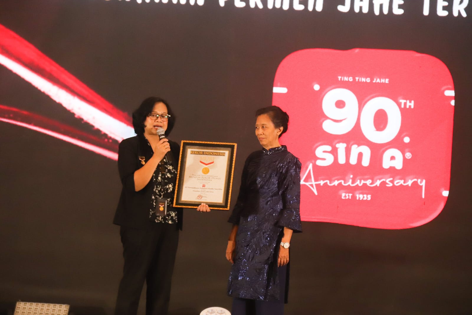 TERLAMA: Perwakilan MURI, Ari Andriani (kiri) menyerahkan piagam penghargaan MURI kepada Dyah Purwaningsih, atas rekor sebagai pemilik permen jahe tertua di Indonesia.(ANDY SATRIA/RADAR SURABAYA)