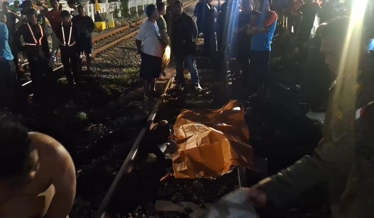 NAHAS : Petugas gabungan mengevakuasi jasad perempuan tertabrak KA Jenggala di perlintasan Jalan Asem Jajar, Bubutan Surabaya, Senin (23/6) malam. (IST/RADAR SURABAYA)