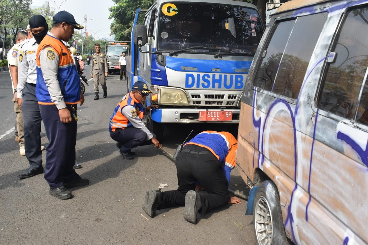 Petugas Dishub Surabaya memindahkan mobil yang parker liar di bahu jalan kawasan Kedungdoro.