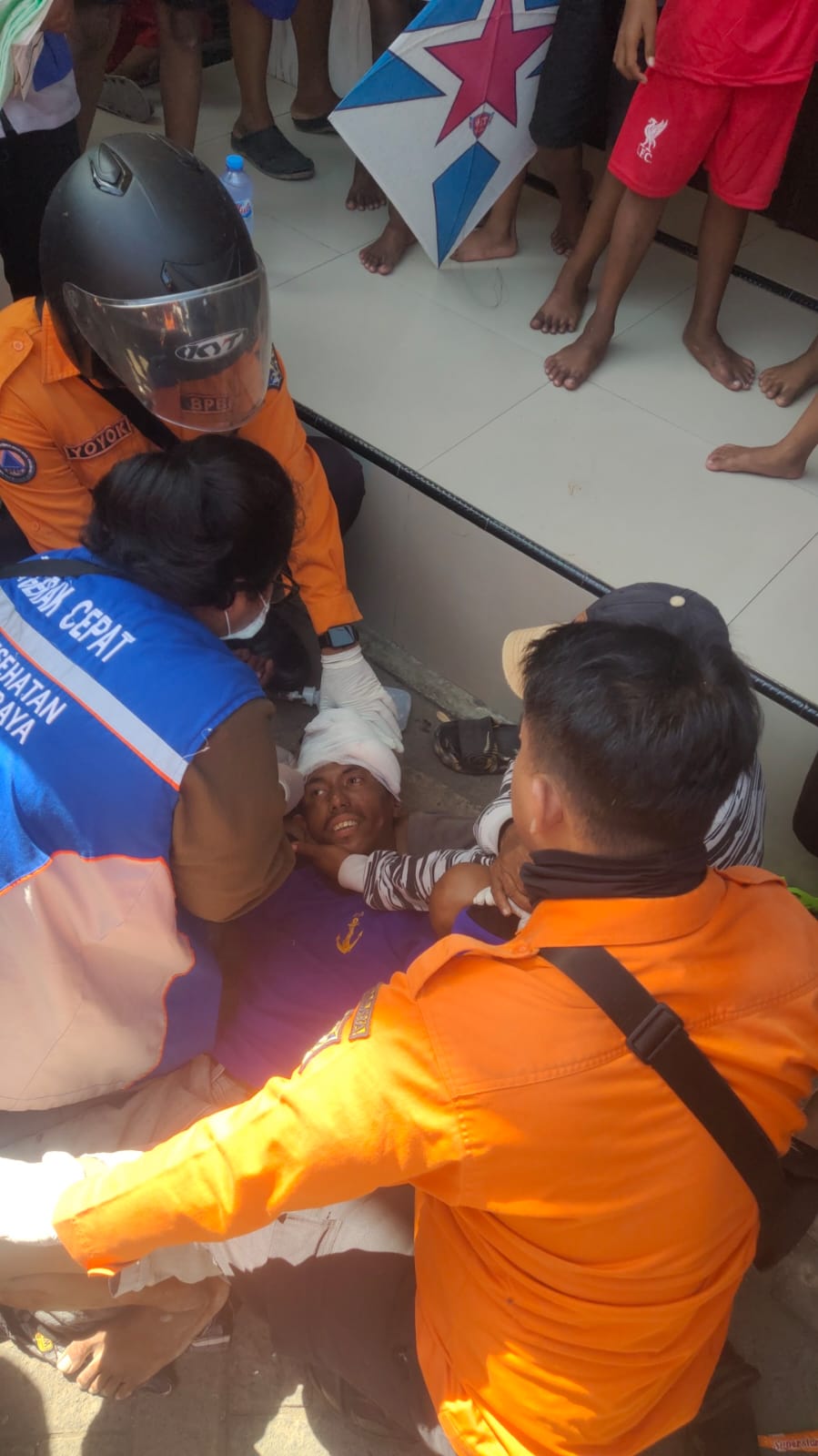 PERAWATAN: Korban saat mendapat perawatan petugas. Penyandang disabilitas ini terserempet KA di Sidotopo Sekolahan, Surabaya. (IST/RADAR SURABAYA)