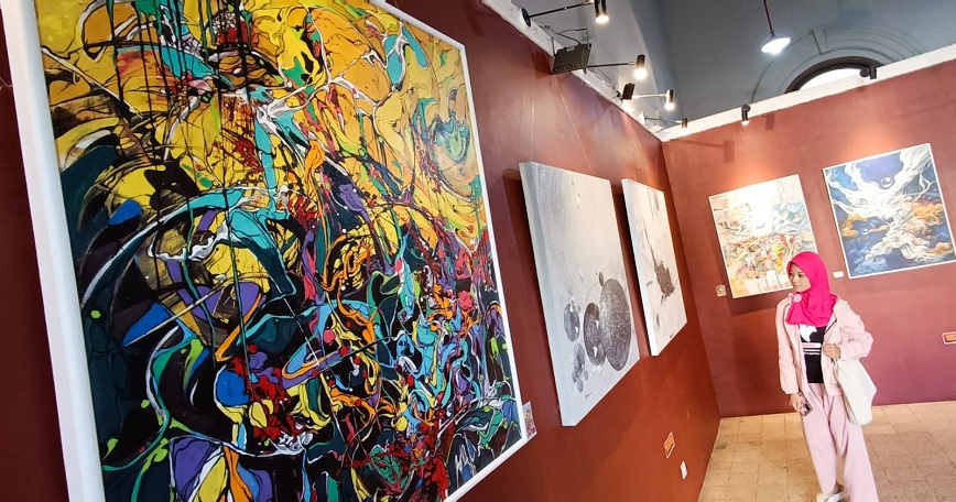 KAGUM: Seorang pengunjung dengan serius memerhatikan sejumlah lukisan hasil goresan perupa Tak Kasat Mata yang menggelar pameran di Galeri Merah Putih Komplek Alun-Alun Kota Surabaya, Senin (7/7).