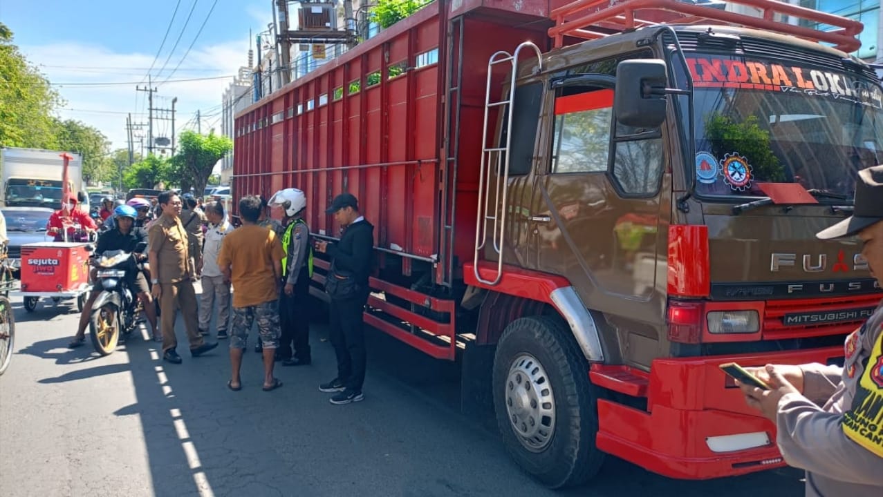 Petugas menggembosi ban truk yang parkir sembarangan di Semut Baru Surabaya. (IST)