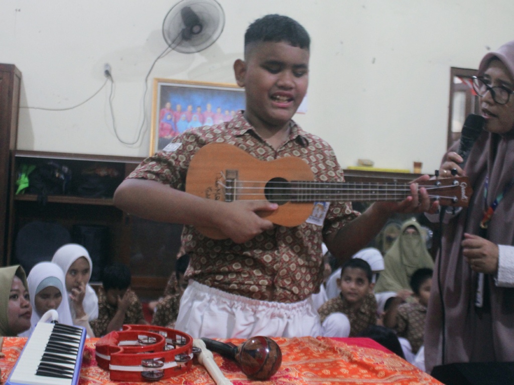 Salah seorang murid tunanetra di Surabaya memainkan ukulele saat MPLS. (Rahmat Sudrajat/Radar Surabaya)