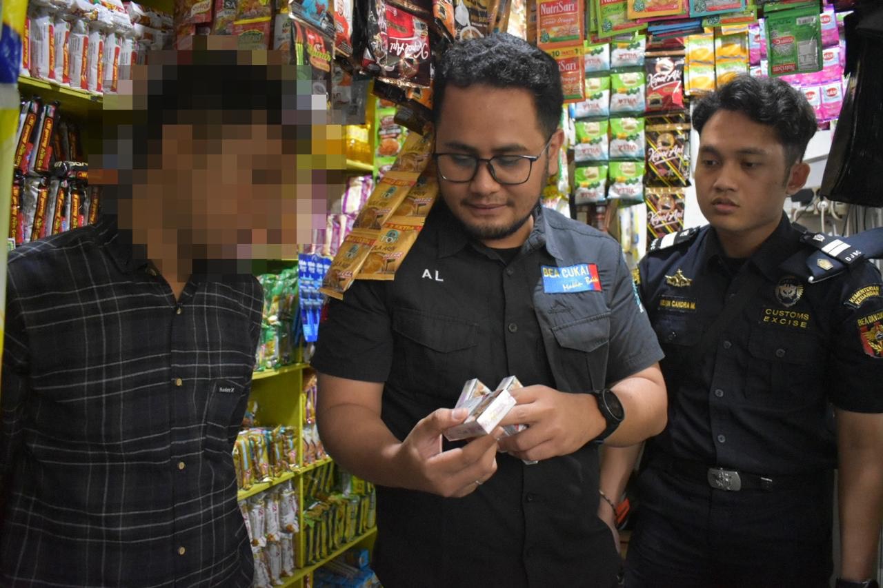 Petugas dari Satpol PP Surabaya dan Bea Cukai Sidoarjo saat melakukan razia rokok ilegal di warung kelontong.