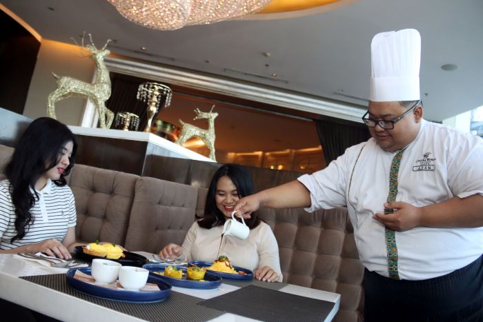 SIRAM SAUS: Sous Chef Hotel Ciputra Surabaya, Adam Citra Ovtavianto (kanan) menuangkan saus teriyaki ke atas twist egg untuk tamunya ketika menikmati menu sarapan di hotel, Minggu (20/7).