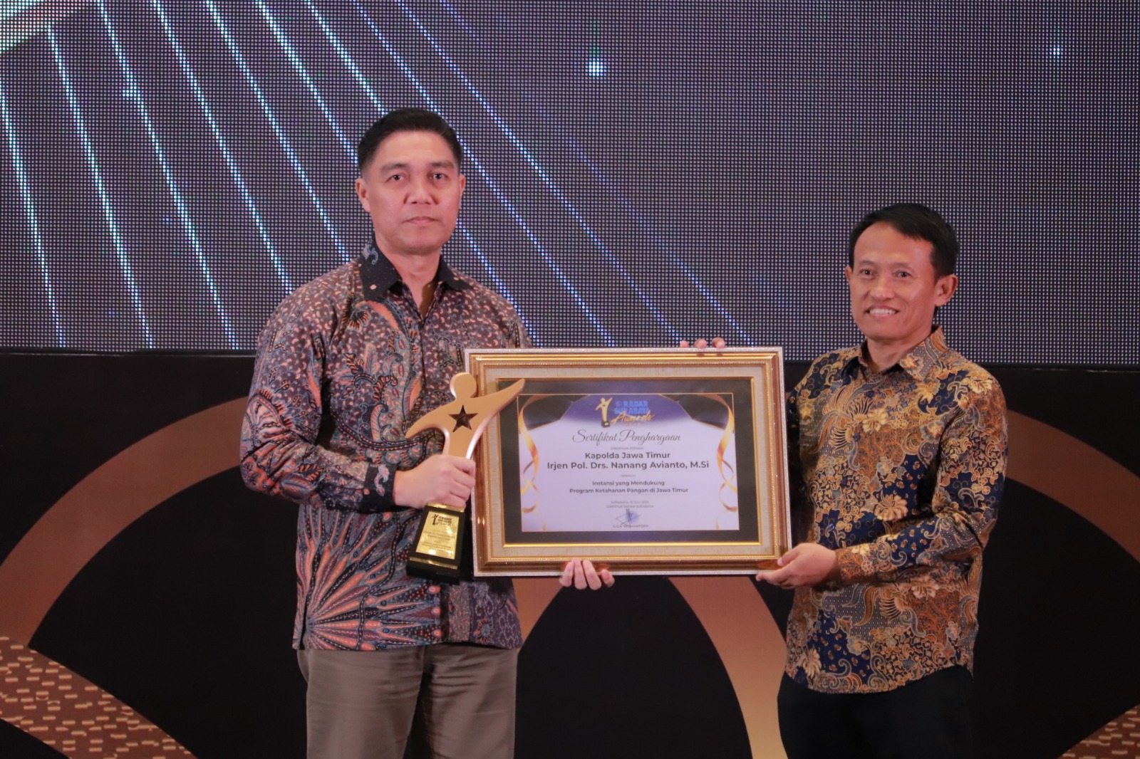 BERBUAH MANIS : Kabid Humas Polda Jatim Kombes Pol Jules Abraham Abast mewakili Kapolda Jatim saat menerima penghargaan Radar Surabaya Award 2025. (SURYANTO/RADAR SURABAYA)