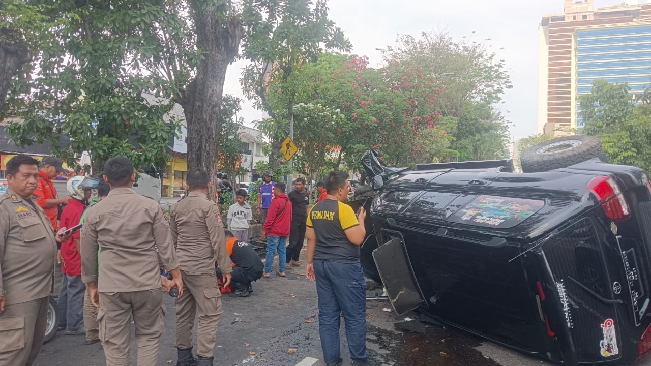 SIGAP : Petugas berada di lokasi mobil Land Cruiser terguling di Jalan Ahmad Yani, Surabaya. Korban langsung mendapat pertolongan dari petugas. (IST/RADAR SURABAYA)