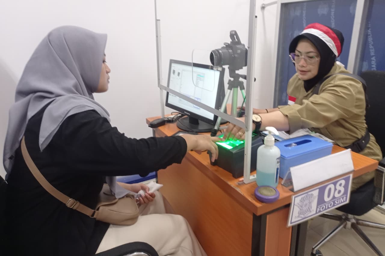 BERBEDA : Petugas Satpas Colombo Satlantas Polrestabes Surabaya melayani pemohon SIM. Mereka mengenakan baju pejuang untuk menyemarakkan HUT RI ke-80. (SURYANTO/RADAR SURABAYA)