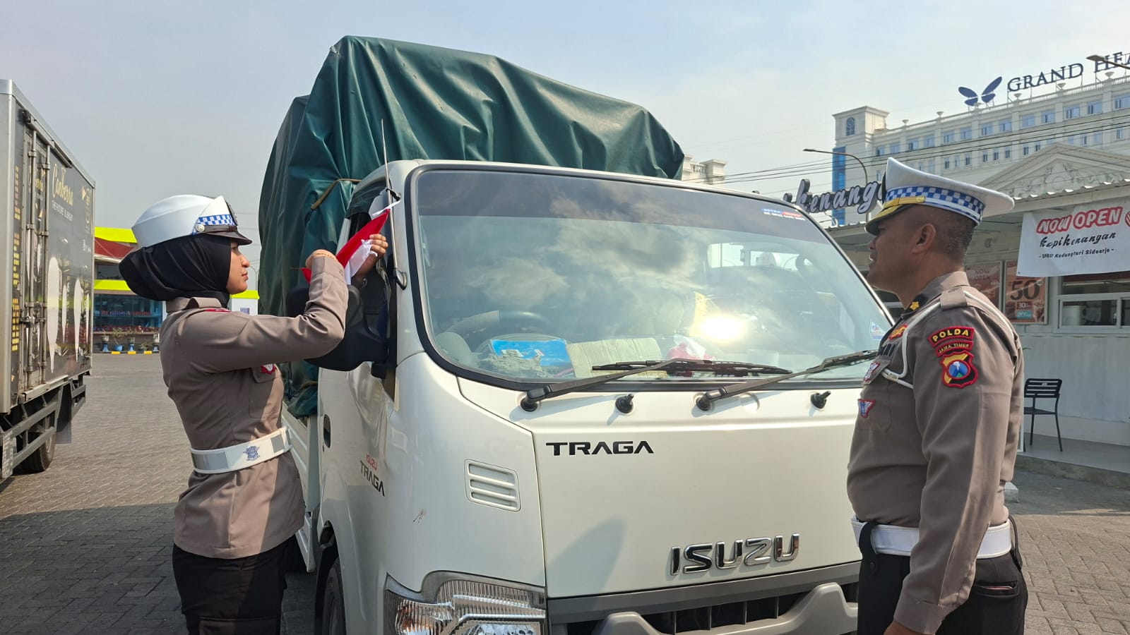 SEMARAK : Anggota Ditlantas Polda Jatim saat memasang bendera merah putih pada sopir truk dan pikap di Surabaya dan Sidoarjo, Kamis (14/8).(MAHRUS/RADAR SURABAYA)