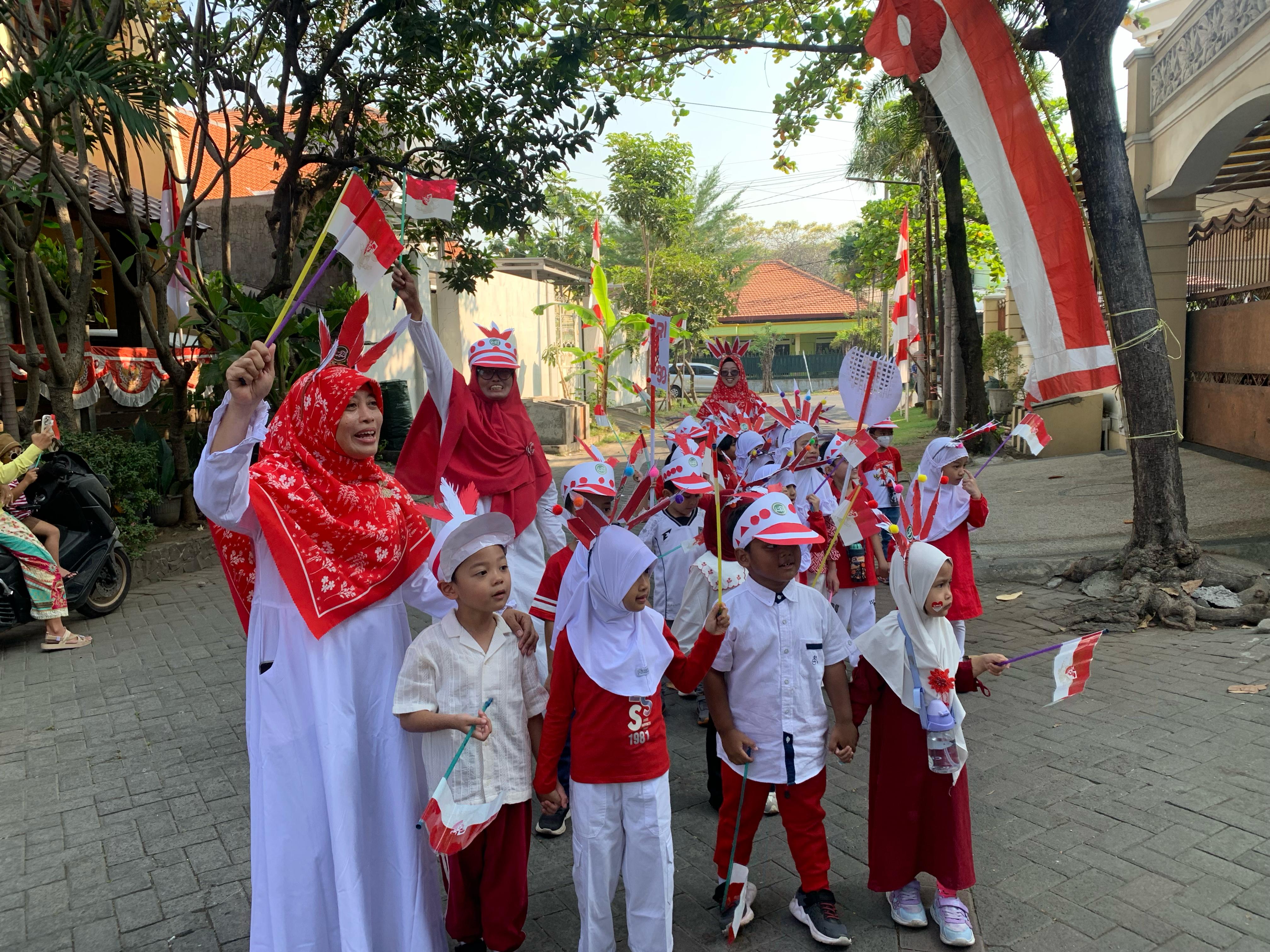 MERIAH: Dewan guru dan anak-anak KB-TK Al Hikmah Surabaya Saat pawai keliling merayakan HUT RI ke-80. (ANAS RADAR SURABAYA)