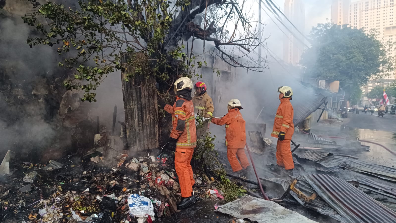 PEMBASAHAN: Petugas DPKP Surabaya berada di lokasi kebakaran. Mereka memastikan api tidak lagi muncul. (IST/RADAR SURABAYA)