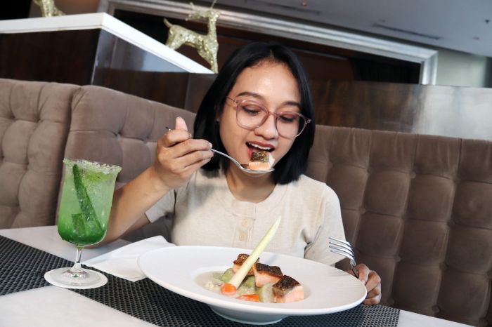 KREASI OPOR SALMON: Juliana Christy, menikmati kreasi menu Opor Salmon yang jarang ditemui di Surabaya, di Ciputra World Hotel Surabaya, Jumat (22/8).