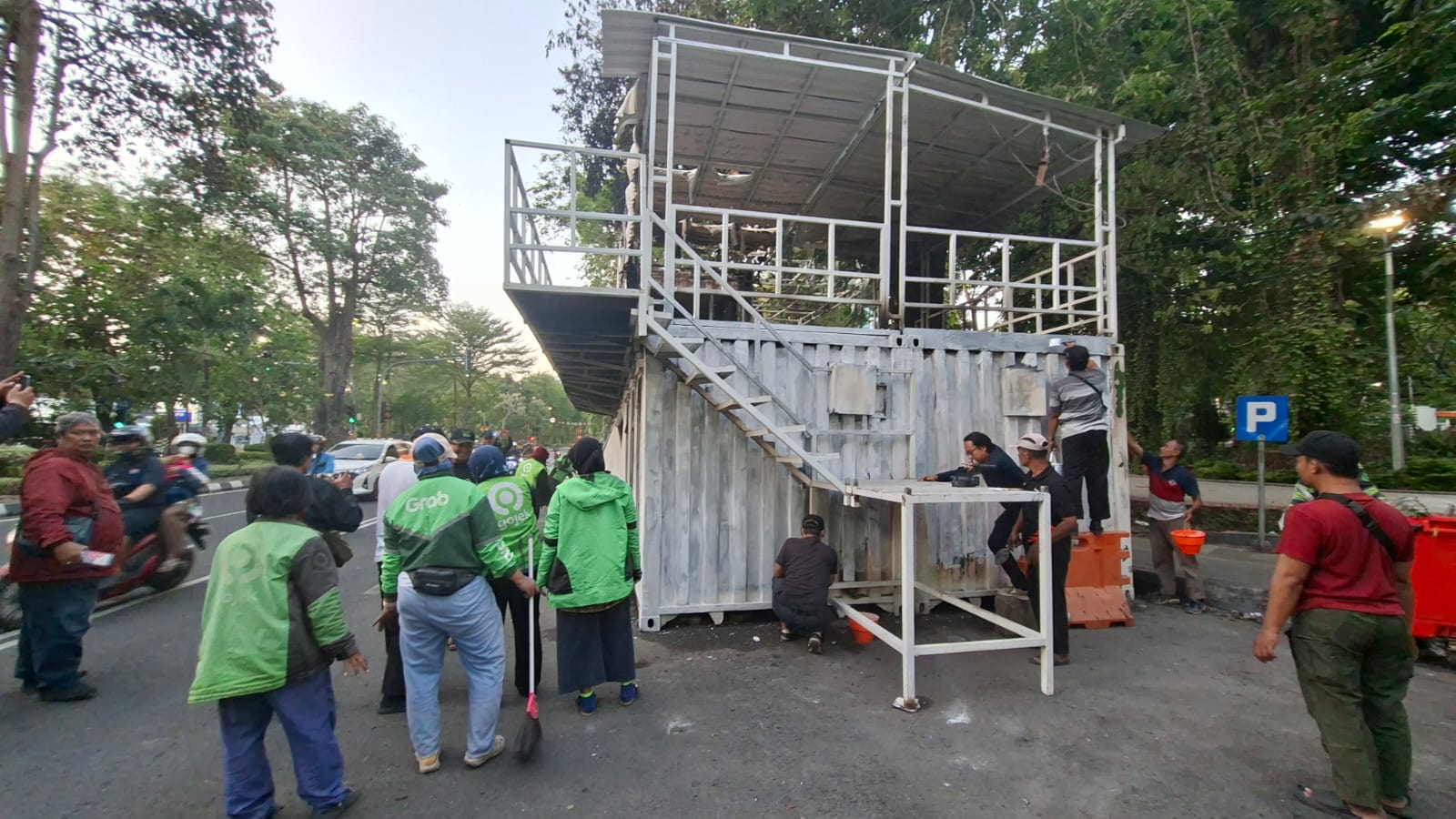 DIBERSIHKAN : Sejumalah driver ojol dan warga membersihkan pos polisi di Taman Bungkul, Surabaya, yang dibakar massa Jumat malam (29/8).(MAHRUS/RADAR SURABAYA)