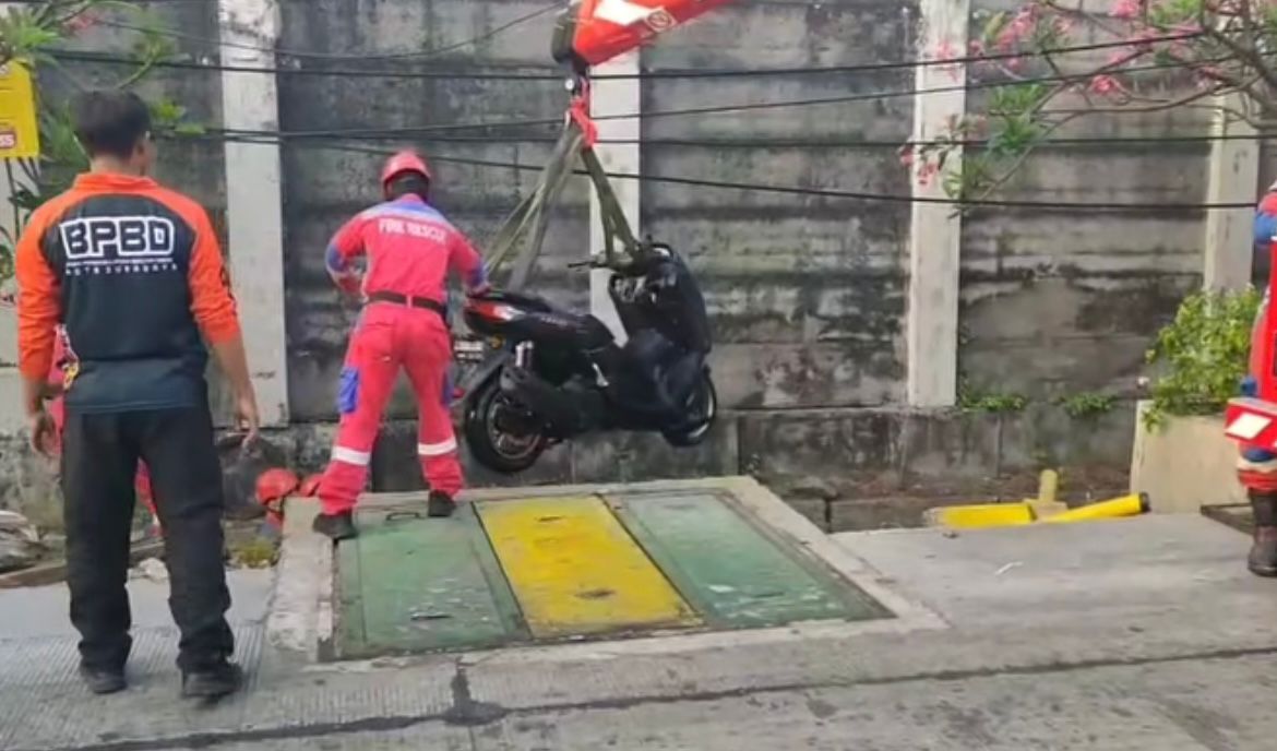 Motor tercebur ke selokan di Jalan Demak, Surabaya. Pengendara selamat, tim rescue berhasil evakuasi kendaraan.
