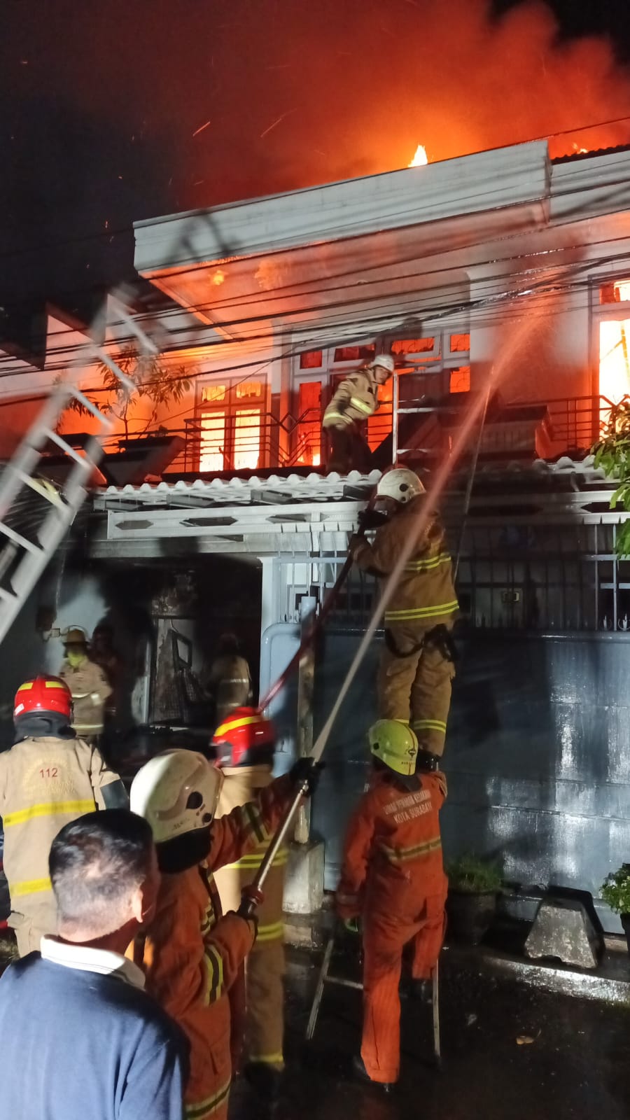 BERJIBAKU: Petugas DPKP Surabaya berusaha memadamkan api yang membakar rumah di Jalan Lebak Arum, Surabaya. (IST/RADAR SURABAYA)