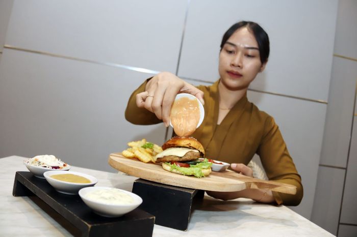 BURGER TIGA SAUS: Indrimencoba burger dengan kreasi tiga saus yang berbeda yang didampingi dengan salad sayur, di Grand Darmo Suites Hotel Surabaya, Minggu (14/9).