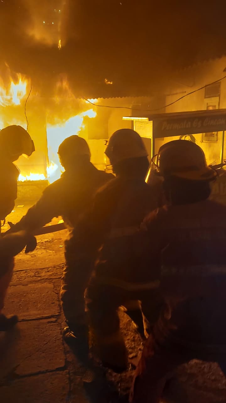 MENYALA: Petugas DPKP Surabaya saat mencoba memadamkan api yang membakar rumah nonpermanen dan kamar kos ini. (IST/RADAR SURABAYA)