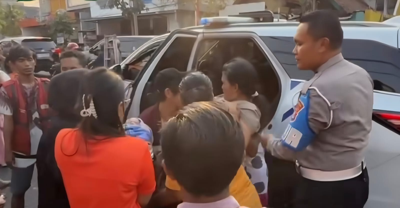 PRIORITAS: Anggota Patwal Gubernur Jatim Khofifah membantu seorang ibu yang melahirkan di Jalan Kutai, Surabaya. (IST/RADAR SURABAYA)